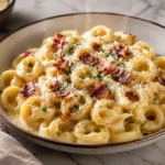 Creamy tortellini carbonara with crispy pancetta, Parmesan, and black pepper on a white plate for an easy dinner recipe