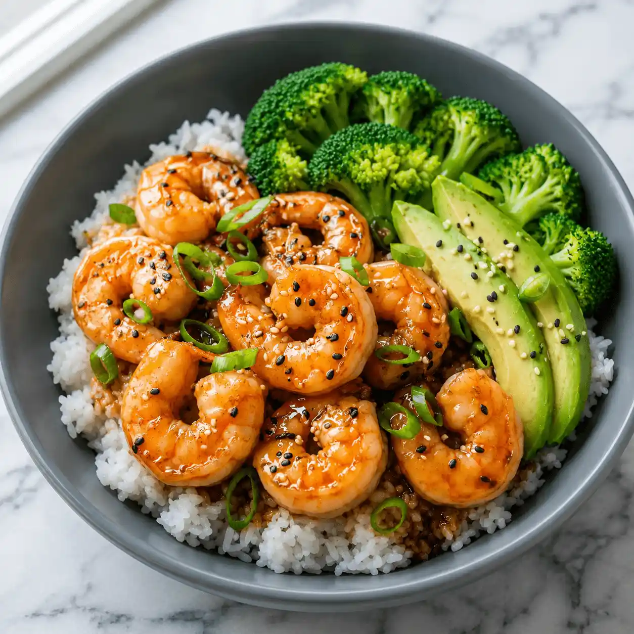 Recipe card featuring a teriyaki shrimp rice bowl with avocado, broccoli, sesame seeds, and green onions on white rice.