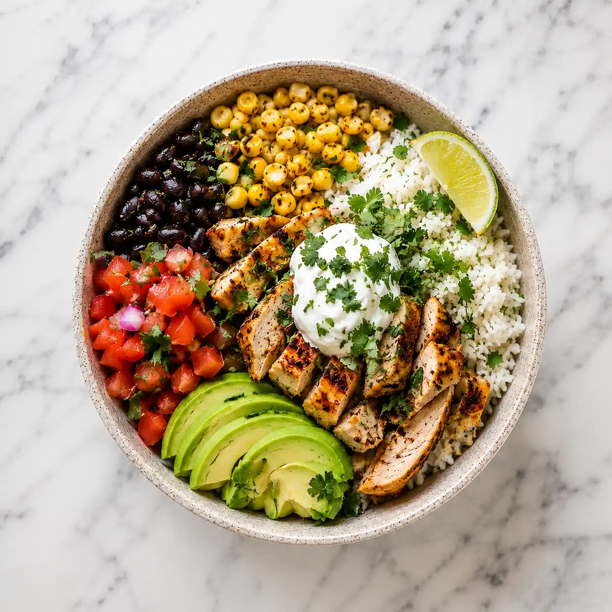 Grilled chicken burrito bowl with rice, avocado, black beans, corn, salsa, sour cream, cilantro, and lime.