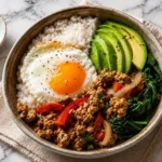 Healthy turkey breakfast bowl with fried egg, avocado, rice, spinach, and peppers served in a ceramic bowl
