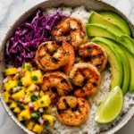 grilled shrimp avocado bowl with mango salsa, purple cabbage, and lime
