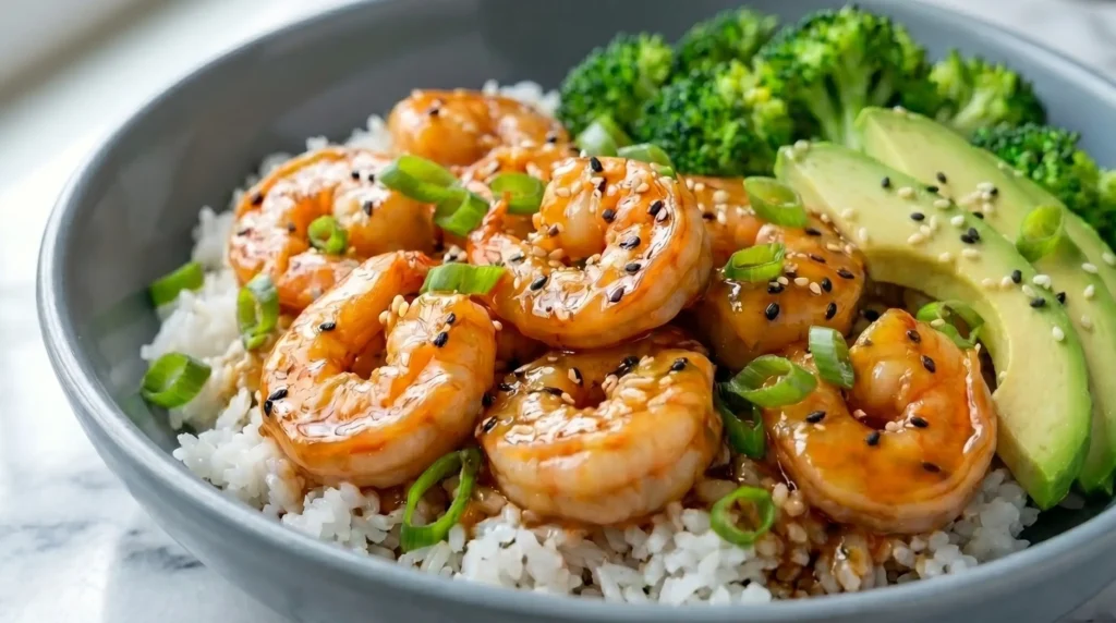 Teriyaki shrimp rice bowl with avocado, broccoli, sesame seeds, and green onions served over fluffy white rice.