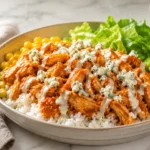 High protein Buffalo Chicken Bowl with rice, lettuce, celery, carrots, blue cheese, ranch drizzle, and spicy buffalo sauce.