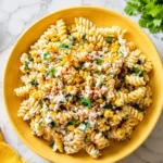 Overhead view of grilled corn elote pasta salad with rotini, charred corn, cotija cheese, cilantro, and Greek yogurt dressing.